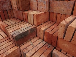 A pile of red bricks neatly arranged, it is used as one of Construction Materials