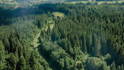 Aerial drone footage of a train moving through scenic mountains near a small settlement. Concept of...