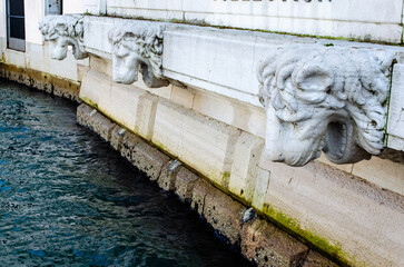 Teste di leone sulla facciata di un palazzo storico di Venezia affacciato sul Canal Grande