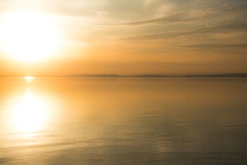 Golden hour sunset reflecting on calm lake with distant mountains creating a serene and tranquil atmosphere