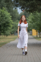 Young beautiful girl in a light dress having fun outdoors on a summer day.