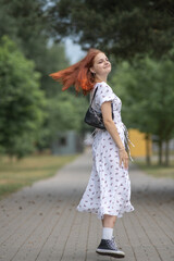 Young beautiful girl in a light dress having fun outdoors on a summer day.