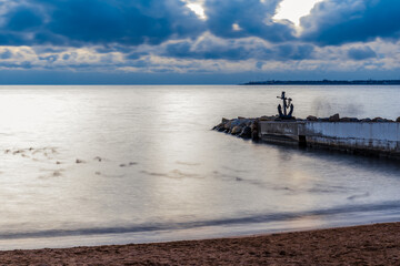 Gelendzhik city. Sea anchor standing on pier on winter stormy day. The sky is cloudy and the water...