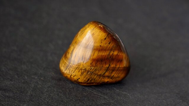 Polished tiger-eye stone on dark background
