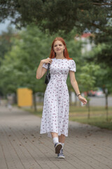 Young beautiful girl in a light dress having fun outdoors on a summer day.
