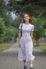 Young beautiful girl in a light dress having fun outdoors on a summer day.