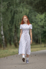Young beautiful girl in a light dress having fun outdoors on a summer day.