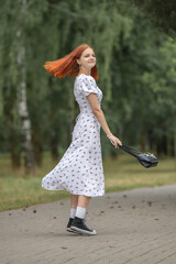Young beautiful girl in a light dress having fun outdoors on a summer day.