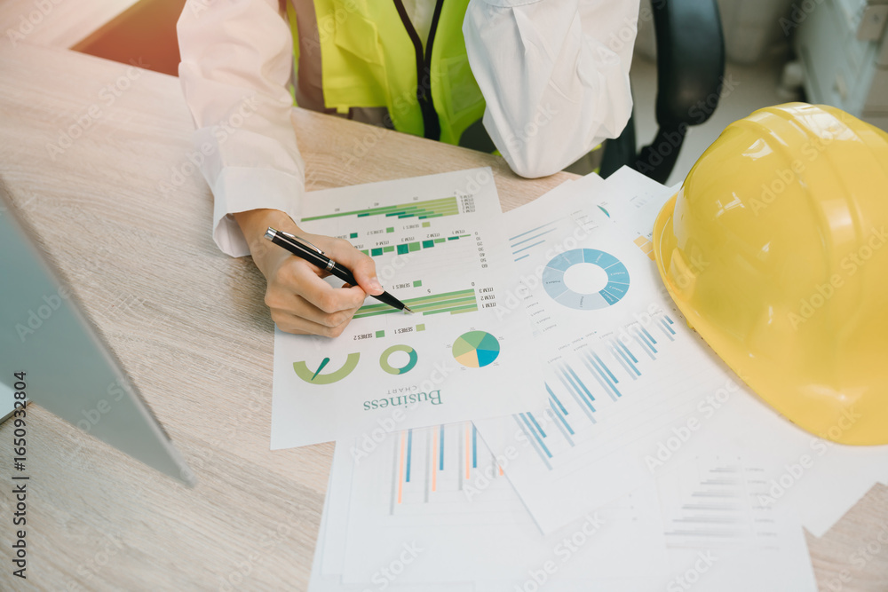 Poster business analysis with charts and graphs by engineer in safety vest with hard hat working on project