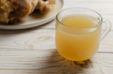 Veal bone broth in a glass cup with ingredients on a white table. Collagen concept. Selective focus. Horizontal orientation. Copy space