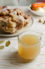 Veal bone broth in a glass cup with ingredients on a white table. Collagen concept. Selective focus. Vertical orientation. Copy space