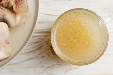 Veal bone broth in a glass cup with ingredients on a white table. Collagen concept. Selective focus. Horizontal orientation. Top view