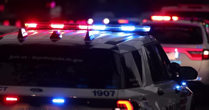 Police units respond to the scene of an emergency with illuminated red and blue lights at dusk.