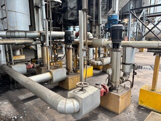 Complex network of pipes, pumps, and motors in an industrial factory setting. This image represents...
