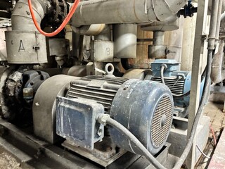dirty industrial electric motor and an intricate web of pipes and valves. The scene conveys the...