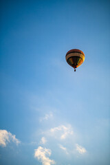 Obraz premium Colorful Hot Air Balloon Flying Against a Clear Blue Sky