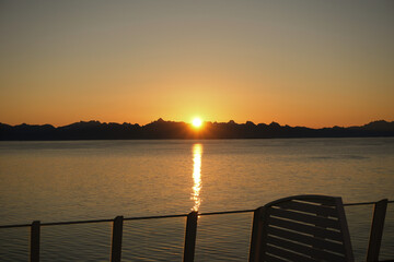 Die Mitternachtssonne hinter den Bergen der Lofoten in Norwegen mit einem orange gefärbten Himmel...