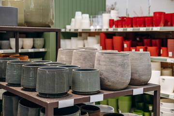Collection of decorative plant pots displayed on shelves in a retail store, showcasing various colors and textures for home gardening enthusiasts