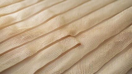 Close-up of beige fabric with layered pleats and fine textured pattern.