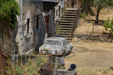 Abandoned vintage car near old stone house.