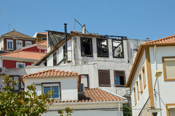 Burned house ruins with damaged roof.