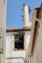 Window and wall of burnt house with destroyed roof after major fire.