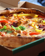 Pizza au poulet, poivrons et chorizo dans sa boîte en carton, photo gourmande et appétissante