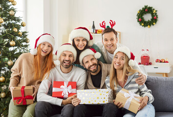 Portrait of a young happy people friends sitting on sofa at home in festive living room with...