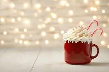 A red mug filled with hot chocolate topped with whipped cream and candy canes against a blurred background.