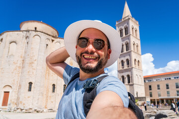 Hombre turista tomándose una selfie en Zadar, Croacia, con la antigua Iglesia de San Donato...