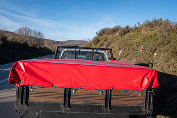 Cargo Secured on a Truck for Transportation The red cover is tied down with blue ropes to protect...
