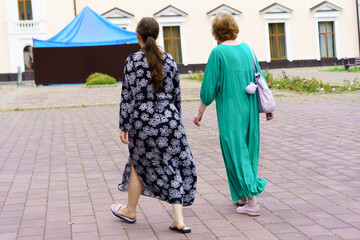 Women walking together in a courtyard during a sunny afternoon in a casual setting