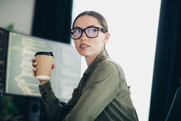 Young female programmer working from home office with a coffee cup, coding and developing software...