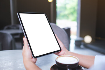 Mockup image of a woman holding digital tablet with blank white desktop screen in cafe