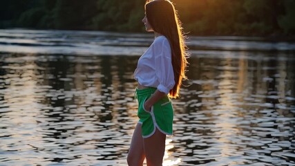 Woman in a green shorts standing in the water. Female standing in the water of a lake. Casual shorts with a serenity at sunset. A woman wearing green shorts is standing in the water lifestyle.