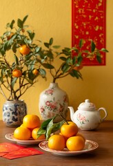 A Chinese New Year scene with red envelopes, an orange tree, and a white porcelain teapot