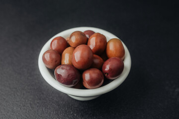 Bowl with red kalamata olives on black textured table