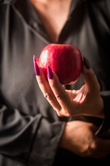 Image of a witch holding an apple in her hand, black background.