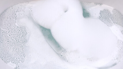 Modern White Bathtub Filled with Running Water from a Brushed Nickel Faucet