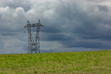Ligne à haute tension sur l'horizon sous un ciel orageux nuageux dans un paysage de campagne avec herbes