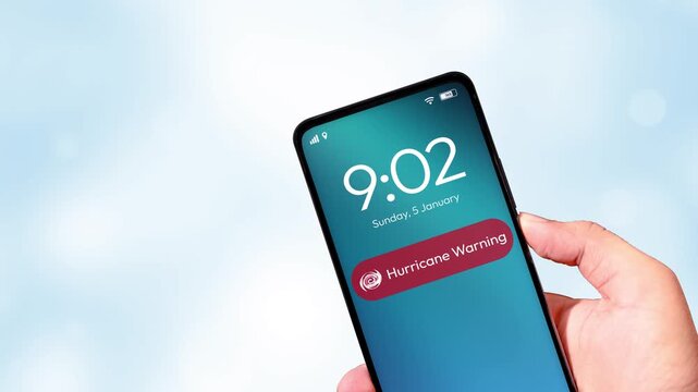 4K video of a hand holding a smartphone that receives a Hurricane Warning push notification. Emergency alerts, natural disaster warnings, and public safety messages