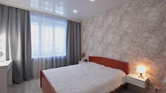 bedroom features a bed, window, gray curtains, textured wallpaper, and a TV