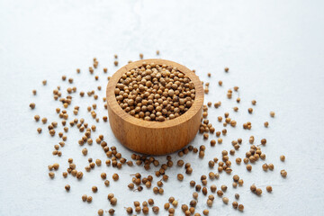 wooden bowl  with coriander seeds on white background