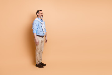 Fototapeta premium Confident mature businessman standing with casual elegance on beige background, showcasing stylish professionalism