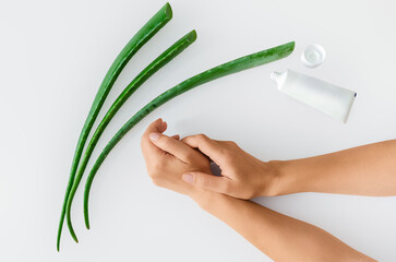 Top view of green aloe vera leaves, cream and woman's hands. Antioxidants, moisturizing hand skin.