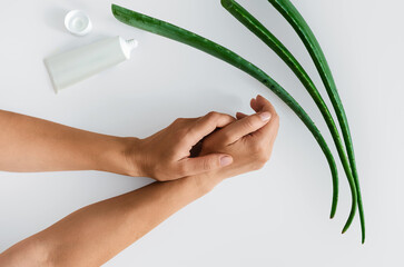 Top view of green aloe vera leaves, cream and woman's hands. Antioxidants, moisturizing hand skin.