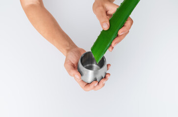 Aloe vera leaf and juice jar in hands on white surface, isolated. Antioxidants, inflammation relief.