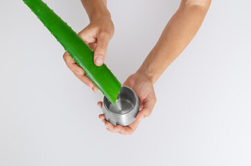 Aloe vera leaf and juice jar in hands on light surface, isolated. Antioxidants, inflammation relief.
