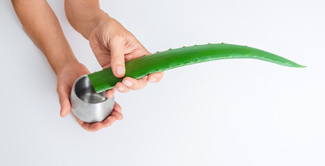 Aloe vera leaf and juice jar in hands on white surface, isolated. Antioxidants, inflammation relief.