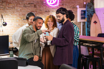 Multi ethnic team collaborating on project using mobile phone in modern office